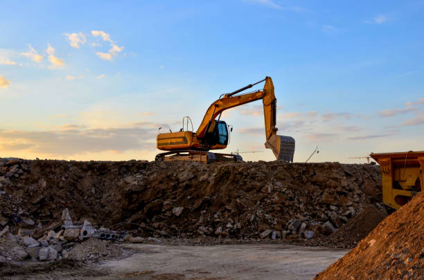 Heavy tracked excavator load stone, old asphalt or concrete waste into a mobile jaw crusher machine. Crushing and processing into gravel for recycling in concrete or cement production. Re-use concrete